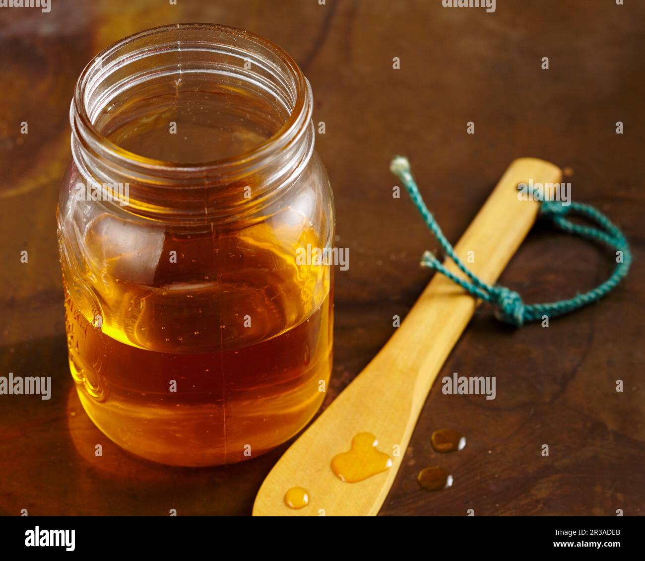 Ein Glas Honig und ein Tropfen Honig auf einem Holzlöffel Stockfoto