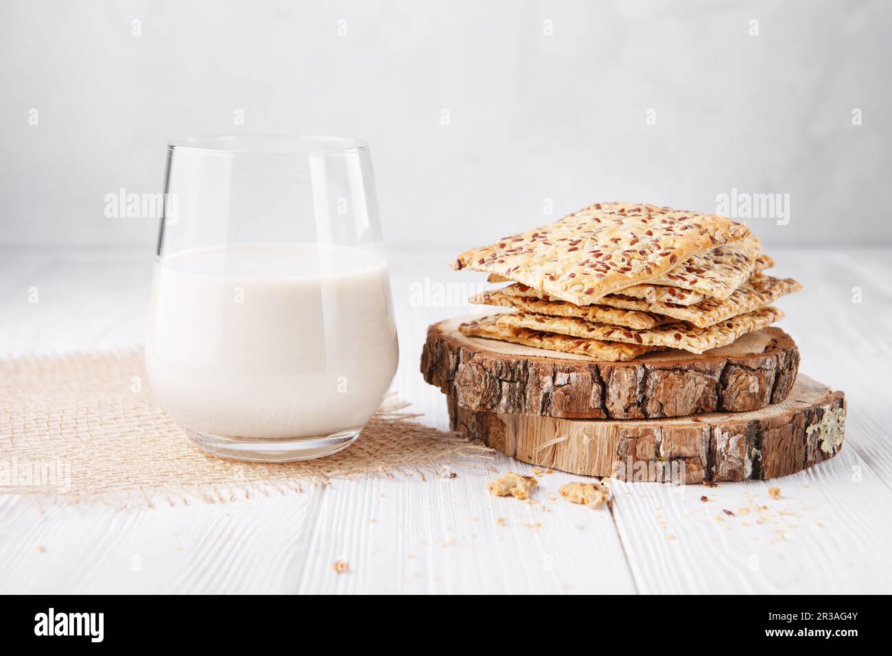 Ein Glas laktosefreie Pflanzenmilch: soja-, Reis-, Hafer- oder Mandelmilch und Kekse mit Sesam, siehe Stockfoto