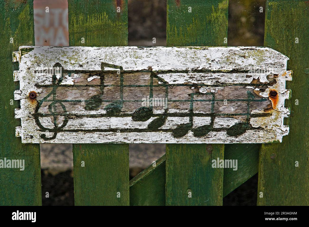 Notizbücher mit Noten und Clef auf einem verwitterten Holzbrett, das an einen grünen Holzzaun genagelt wurde Stockfoto