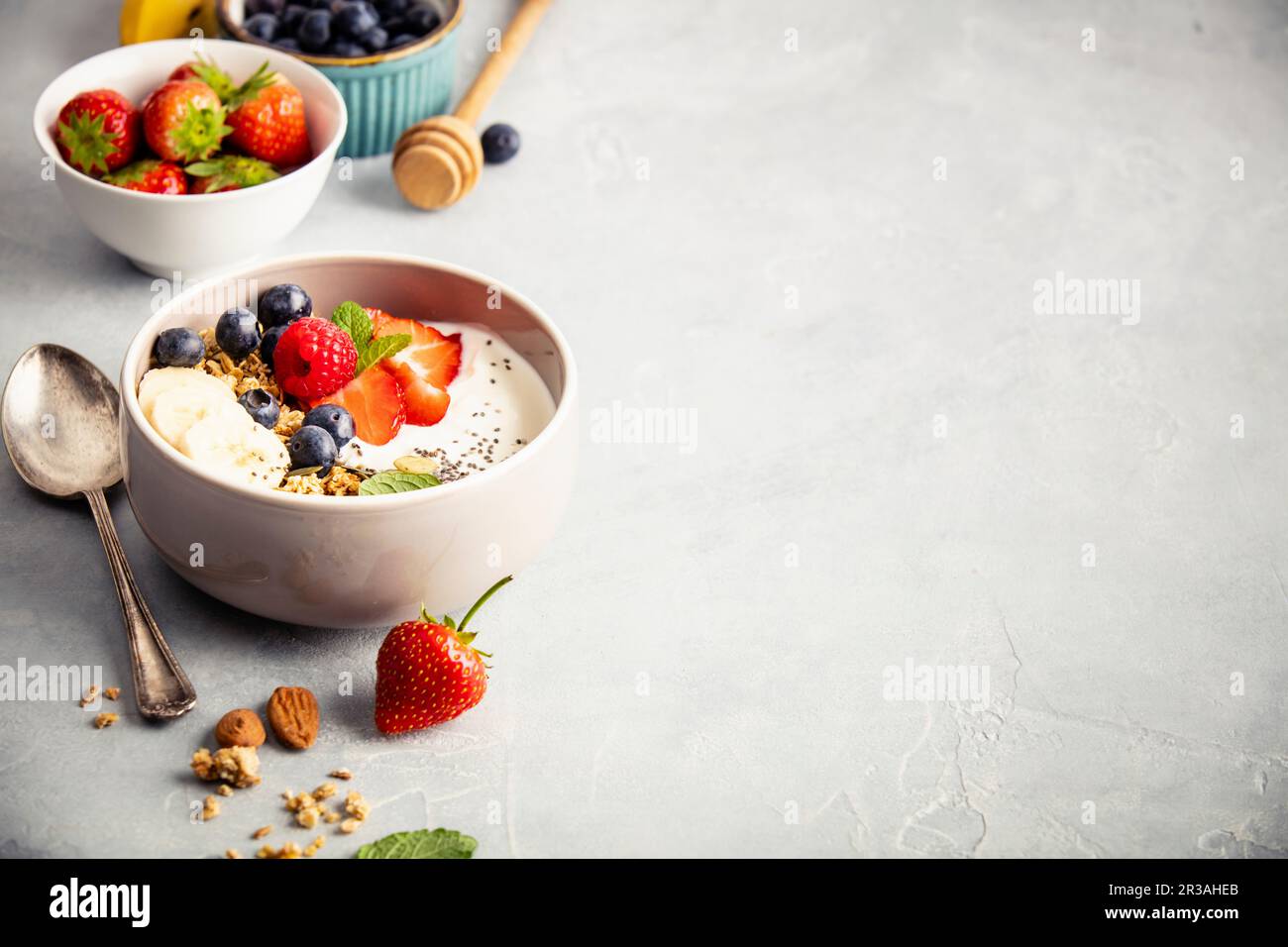 Hafergranola mit frischen Beeren, Banane, Joghurt, Chiasamen und Minzblättern Stockfoto