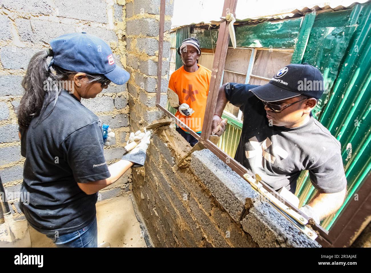 Das Community Outreach-Programm hilft beim Bau eines Fensterrahmens auf einem kleinen, erschwinglichen Haus in einer lokalen Gemeinde Stockfoto