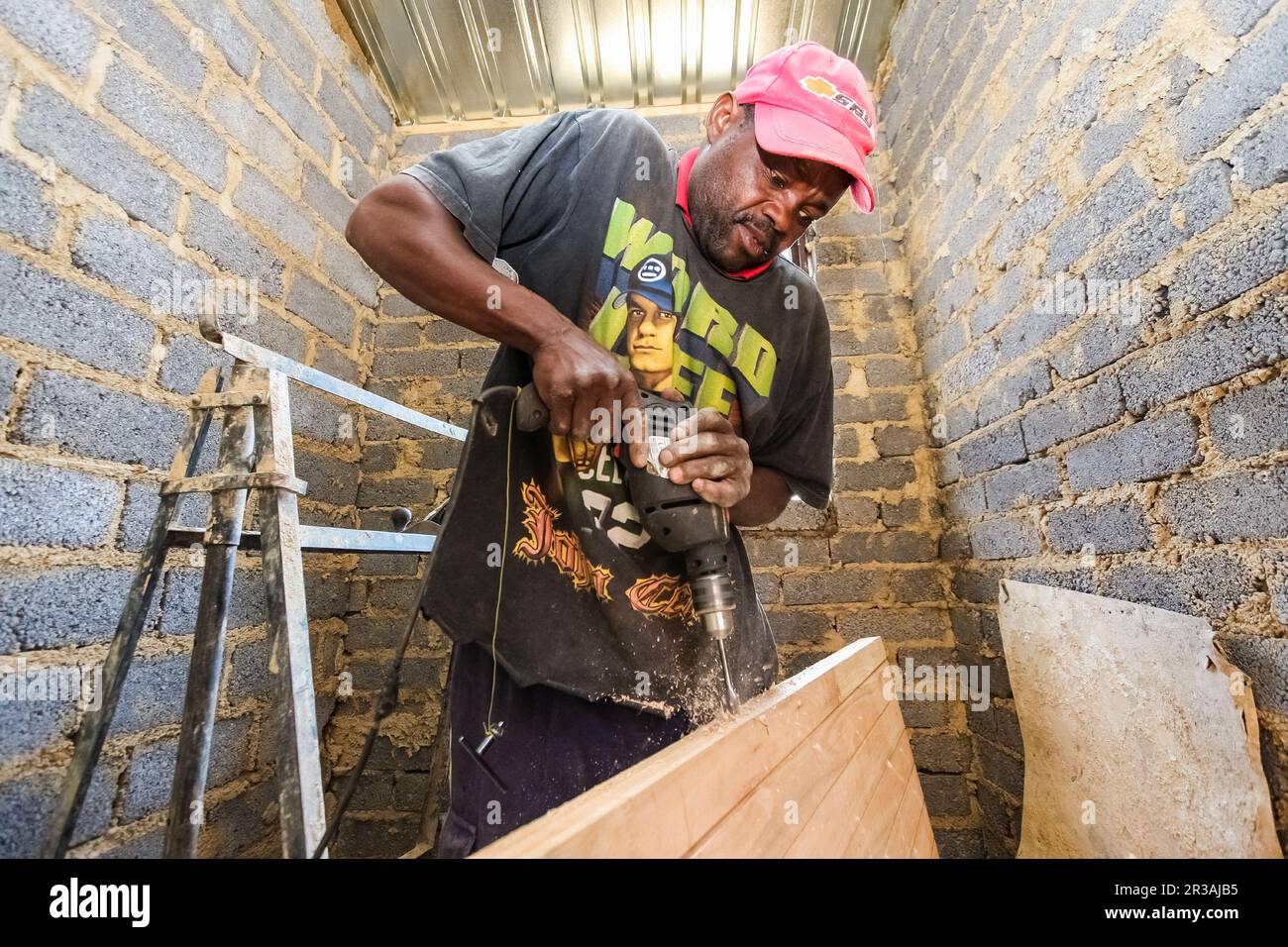 Afrikanischer Zimmermann arbeitet an einem Gemeindeverbandprogramm, um ein kleines, erschwingliches Haus in einer lokalen Gemeinde zu bauen Stockfoto