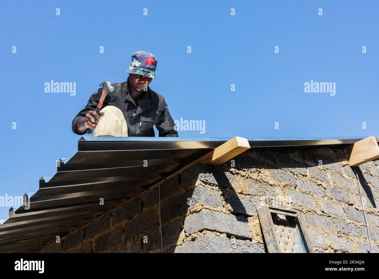 Das Community Outreach-Programm hilft bei der Installation von Metalldächern in einem kleinen, erschwinglichen Haus in einer lokalen Gemeinde Stockfoto