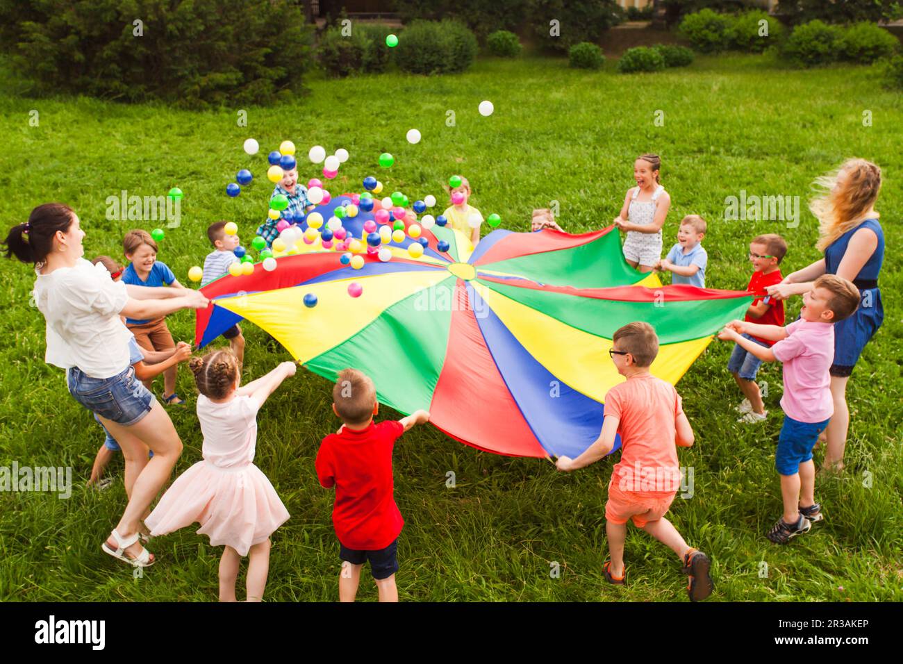 Geburtstagsspiele an der frischen Luft mit Fallschirm und Kugeln Stockfoto