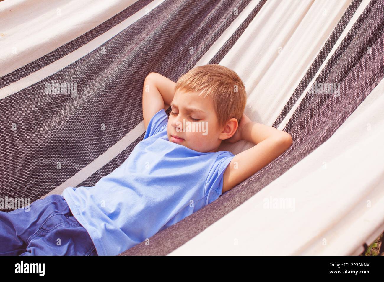 Vorschooljunge, der am Sommertag in einer Hängematte liegt Stockfoto