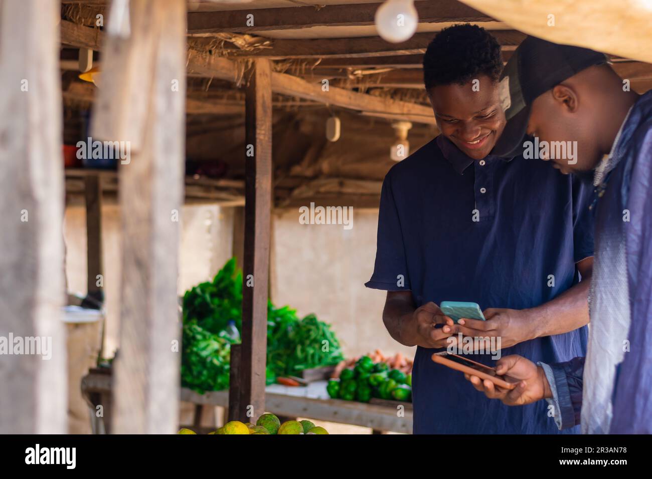 Afrikanischer Marktmann und Kunde, der Transaktionen zur Bezahlung auf einem afrikanischen Markt durchführt, Mann bezahlt Rechnungen. Bargeldloses Policy-Konzept, Internet-Banking Stockfoto