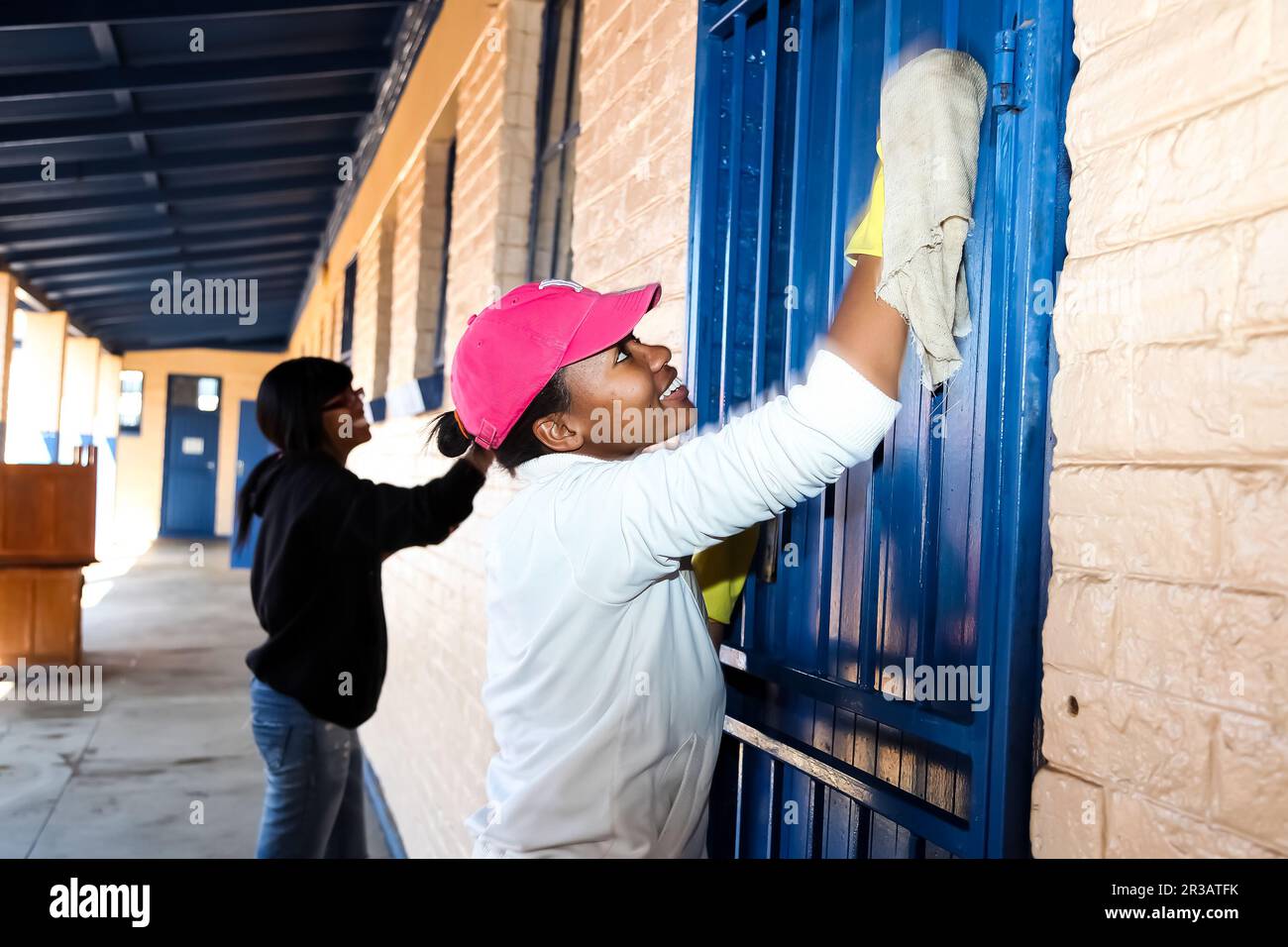 Afrikanische Frauen, die gemeinnützige Reinigungsarbeiten an der Gemeindeschule durchführen Stockfoto