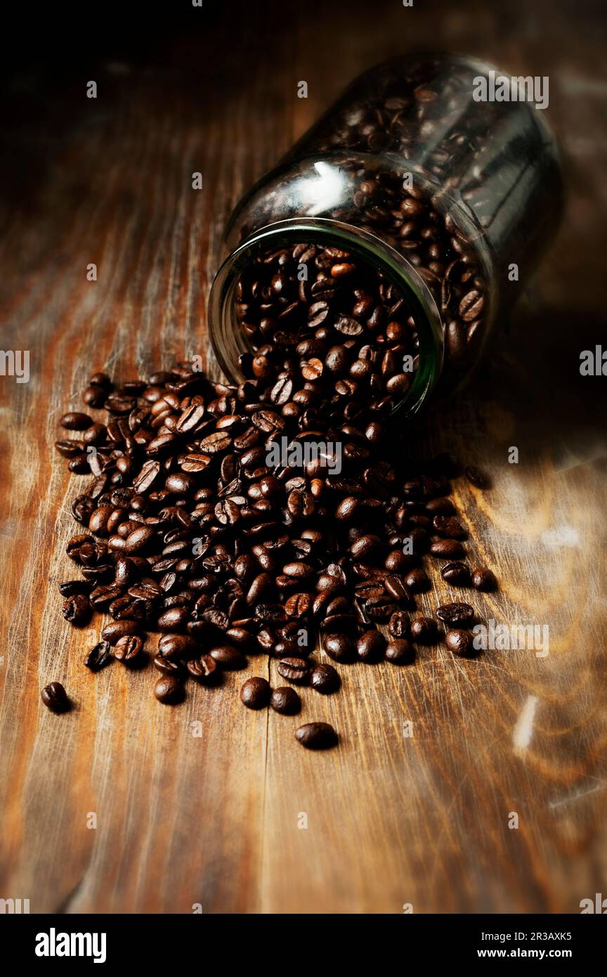 Kaffee Bohnen auf einem Holztisch und in einem Glas Stockfoto