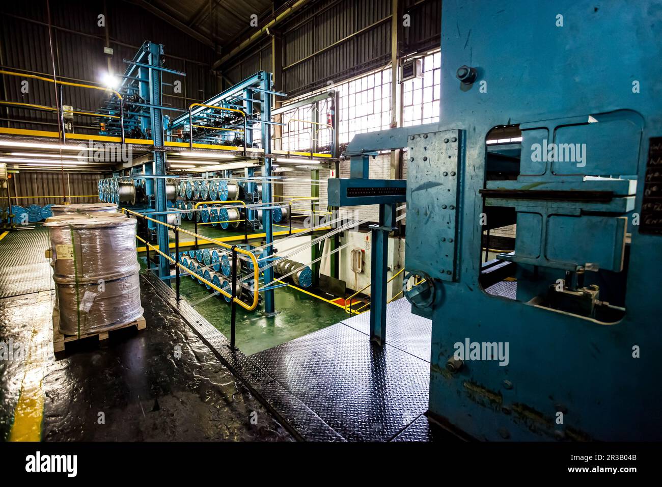 Weitwinkelansicht der Kabelspulen einer großen Maschine in einer Förderbandfabrik Stockfoto