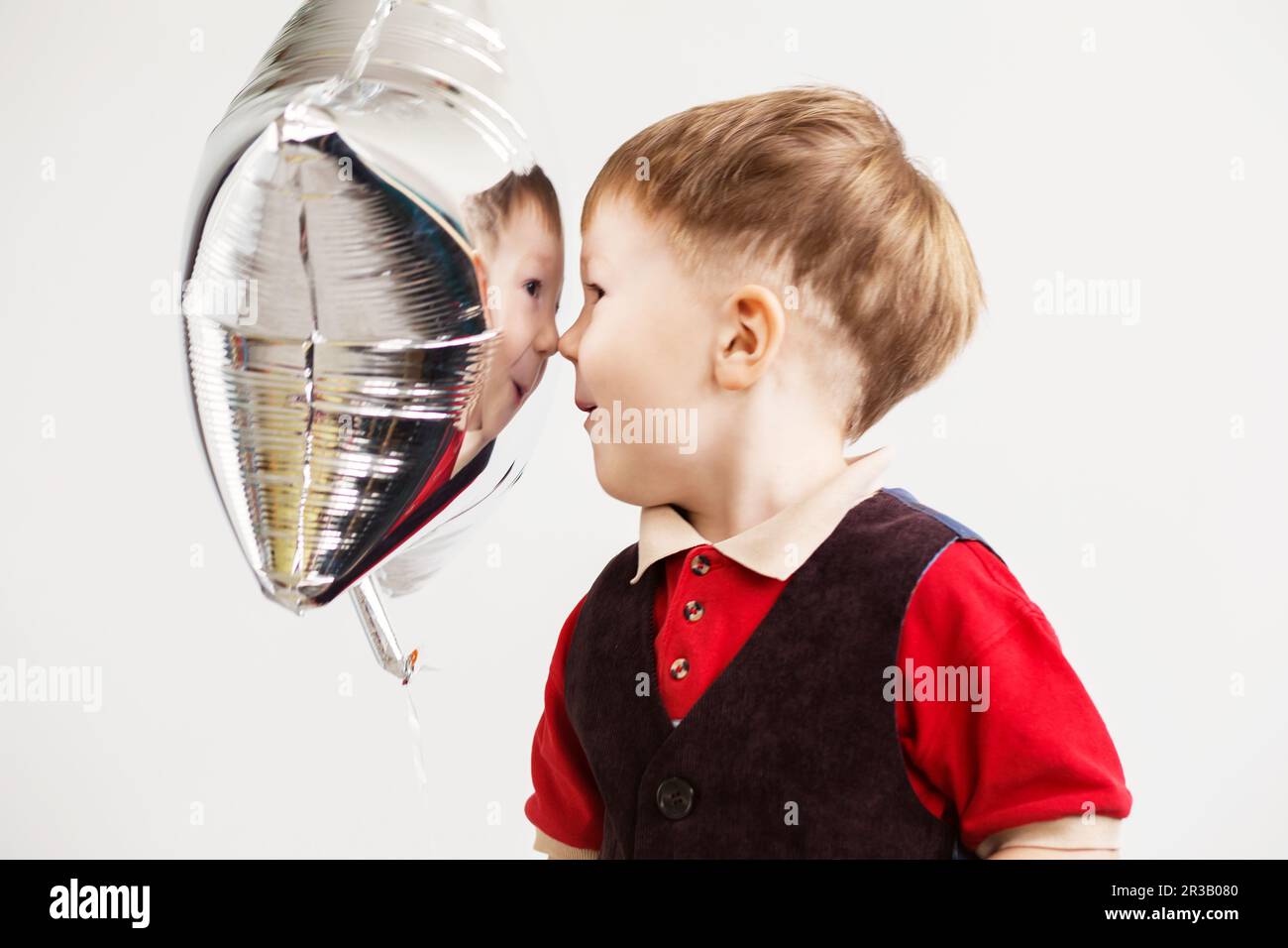 Ein Junge, der im Studio mit sternförmigen Ballons Affe spielt. Der Junge sieht und freut sich über seinen Stockfoto