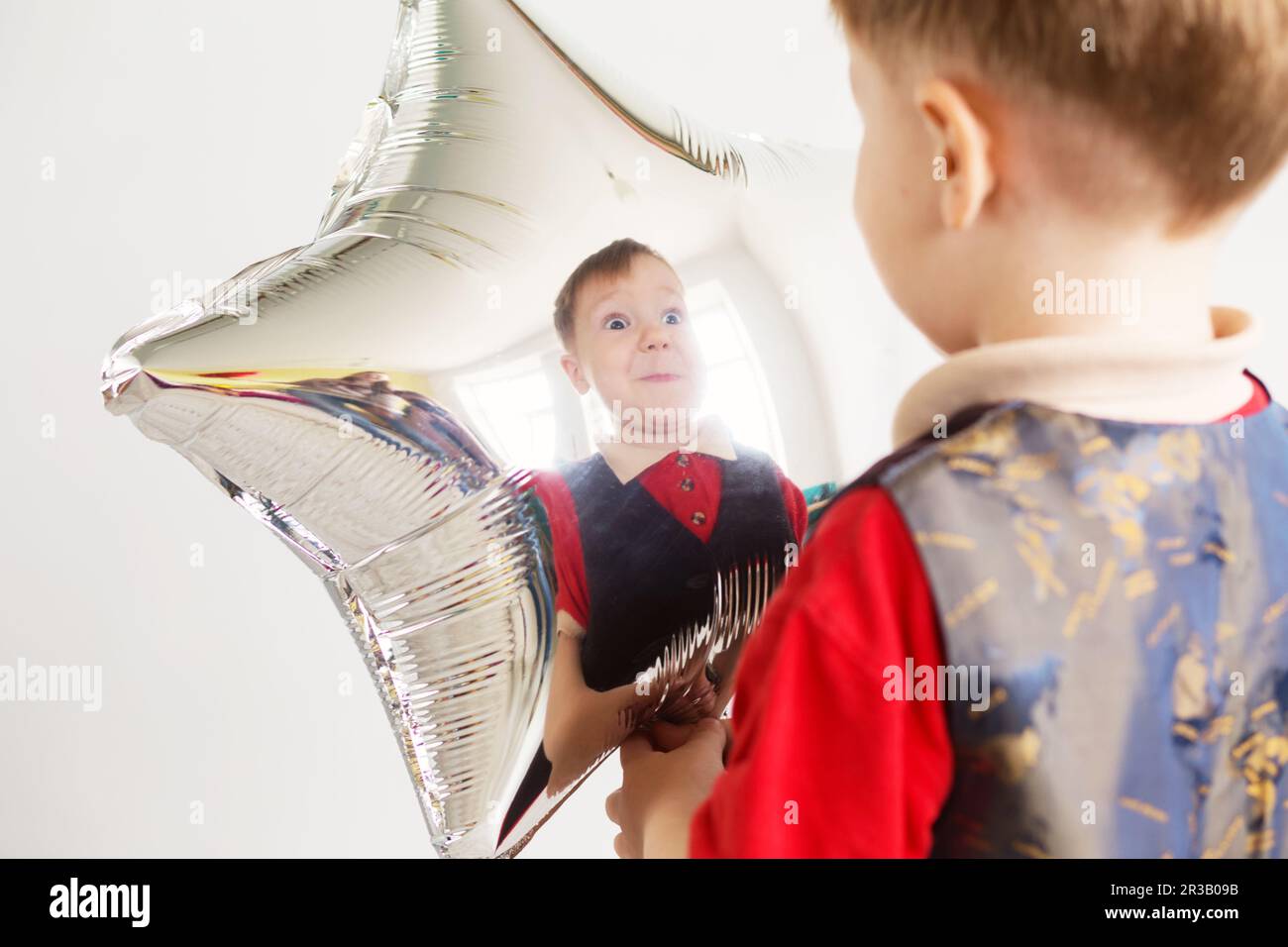 Ein Junge, der im Studio mit sternförmigen Ballons Affe spielt. Der Junge sieht und freut sich über seinen Stockfoto