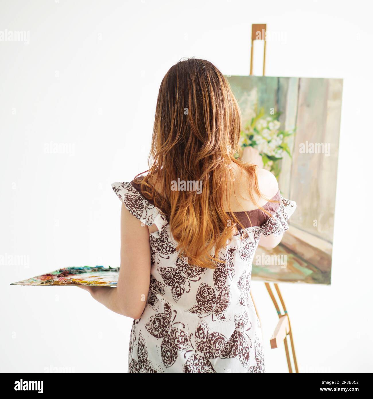 Frau Gemälde auf einer Leinwand vor weißem Hintergrund. Rückansicht. Stockfoto