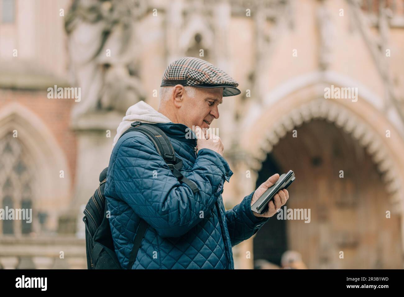 Ein älterer Mann mit Smartphone, der vor der Kathedrale steht Stockfoto