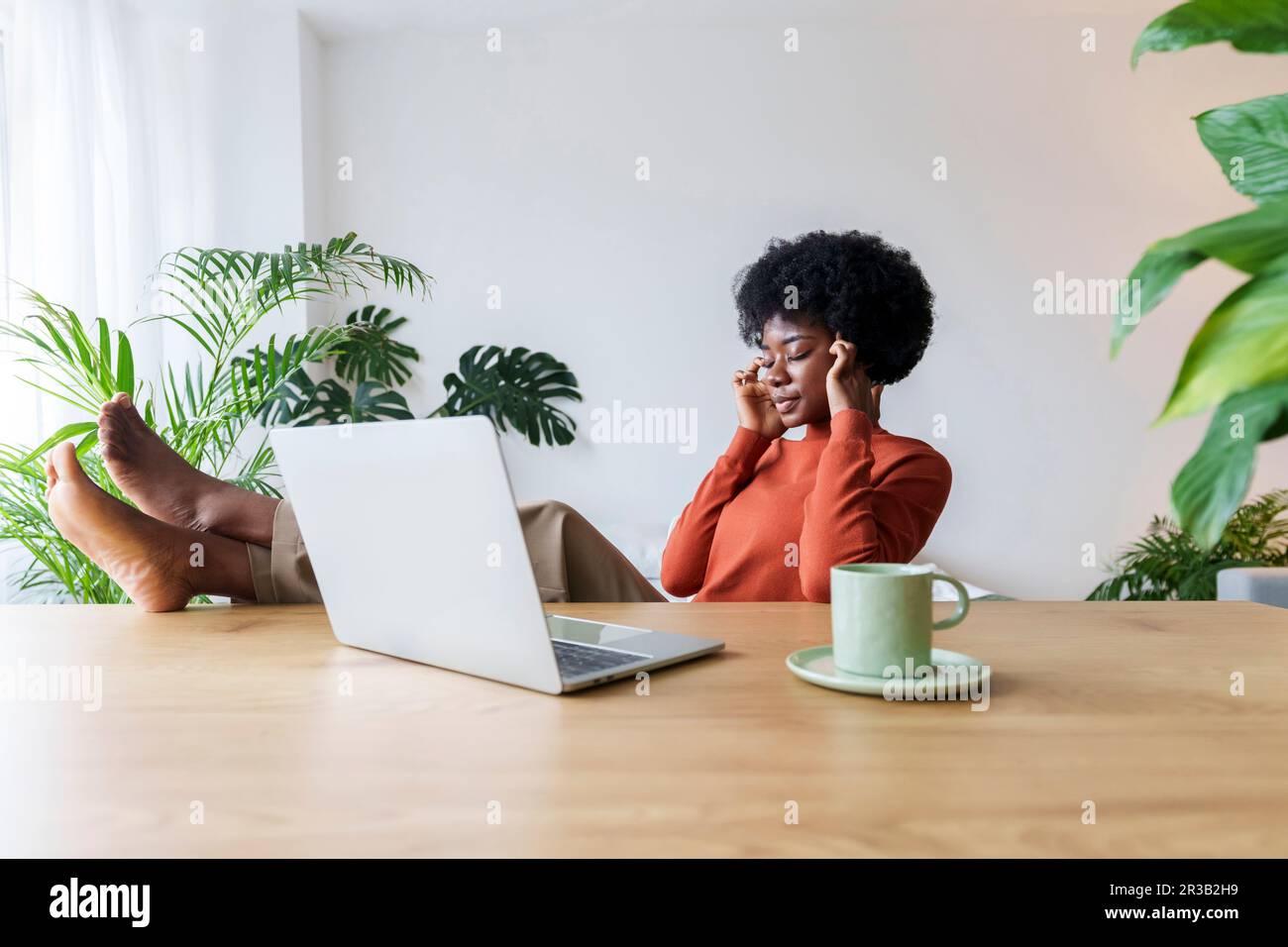 Aufmerksame Geschäftsfrau, die mit geschlossenen Augen am Schreibtisch sitzt Stockfoto