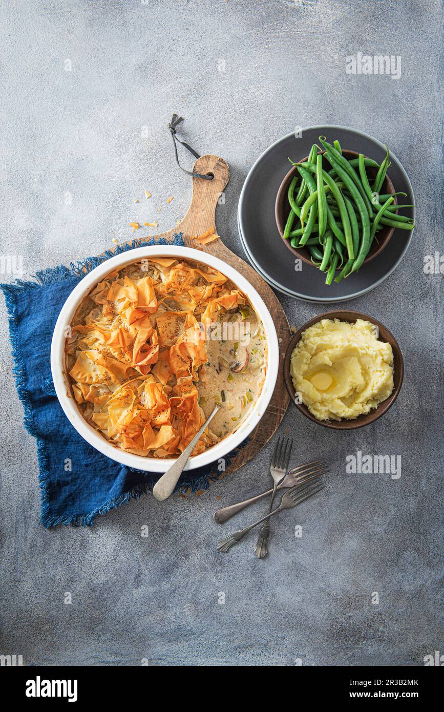 Hühnchen, Lauch- und Pilzkuchen mit Filo-Gebäck, Kartoffelpüree und Bohnen Stockfoto