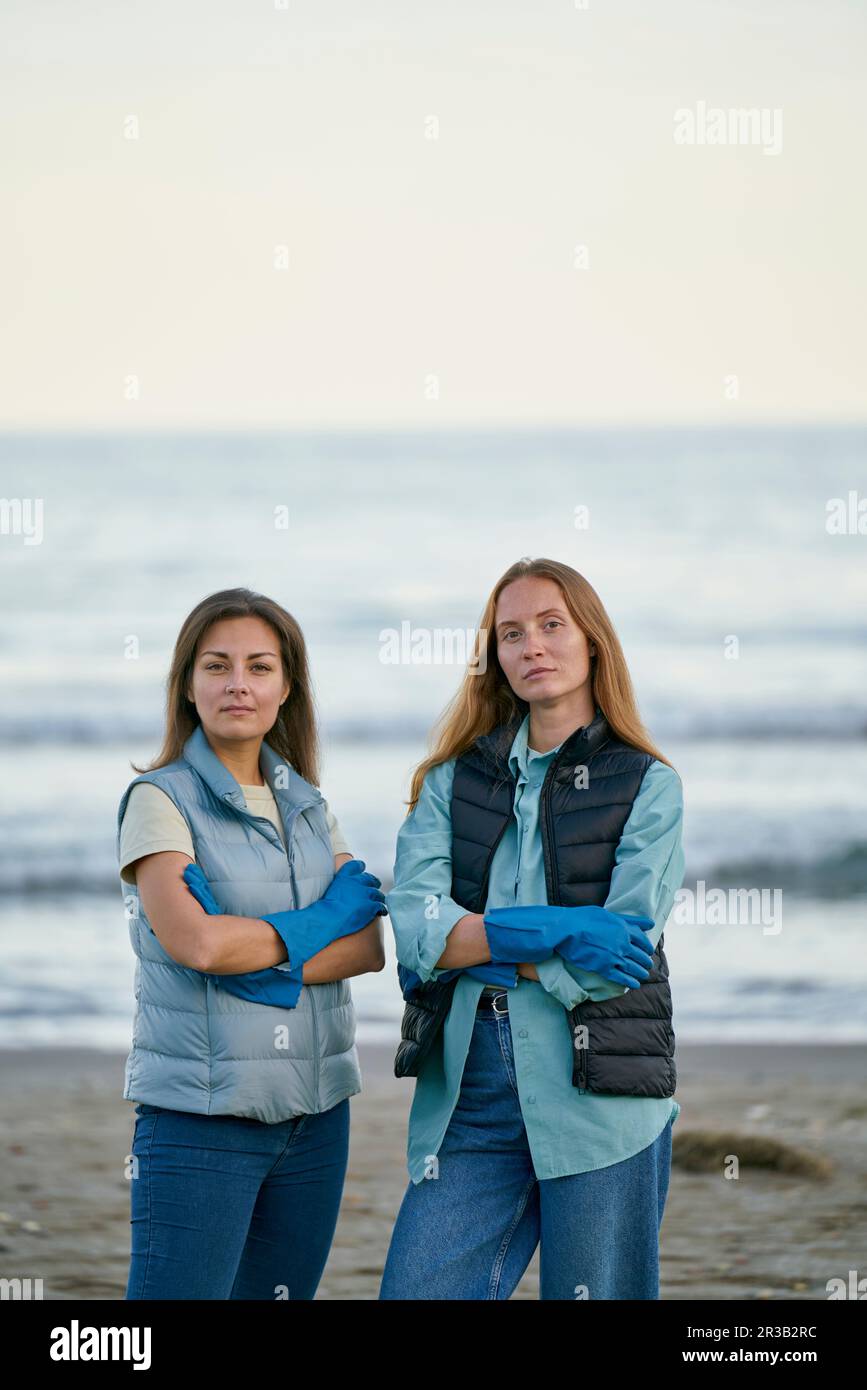 Selbstbewusste Freiwillige, die am Strand mit gekreuzten Armen stehen Stockfoto