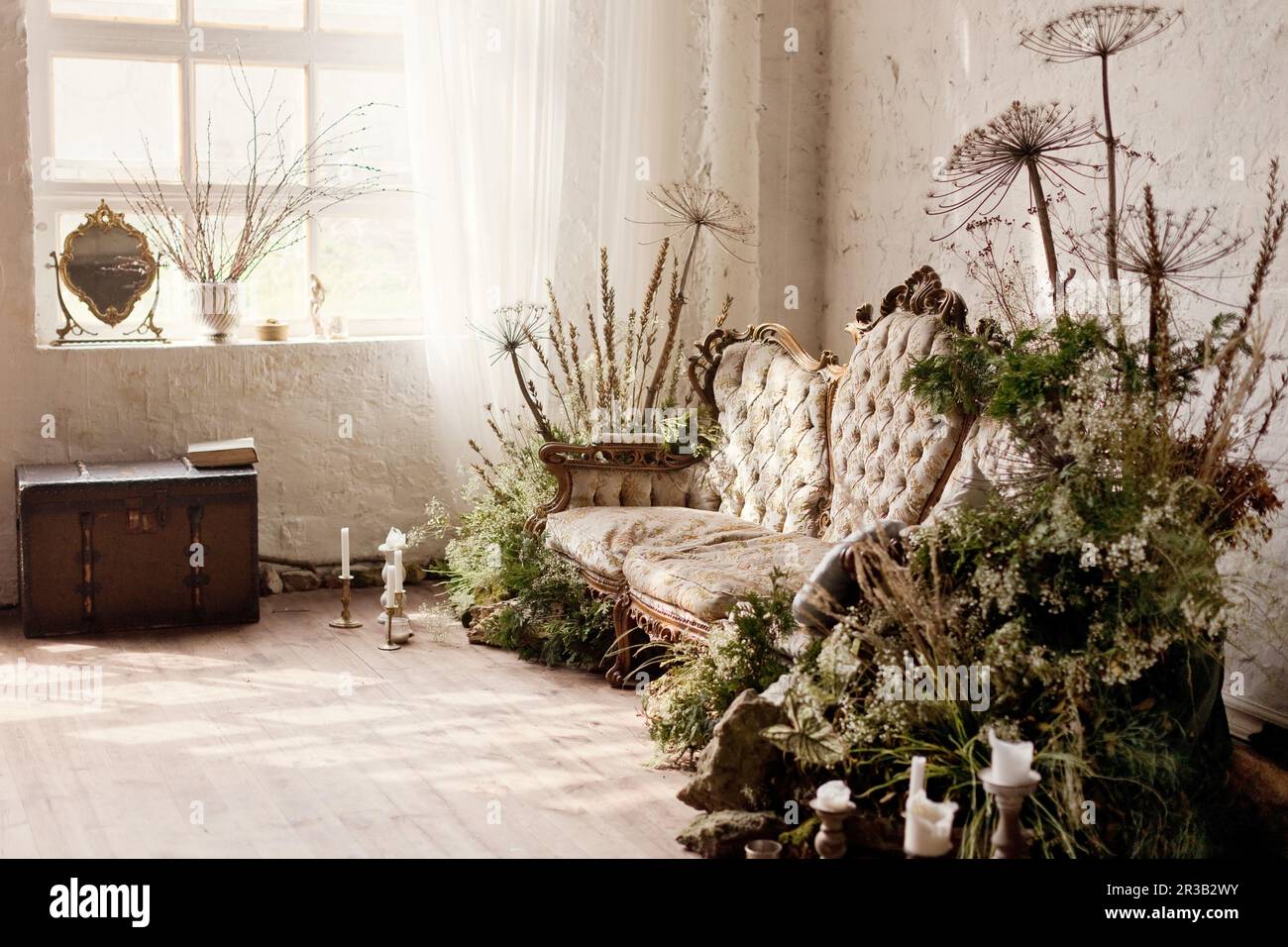 Oldtimer-Sofa mit trockenen Blumen und Pflanzen im Loft-Apartment Stockfoto