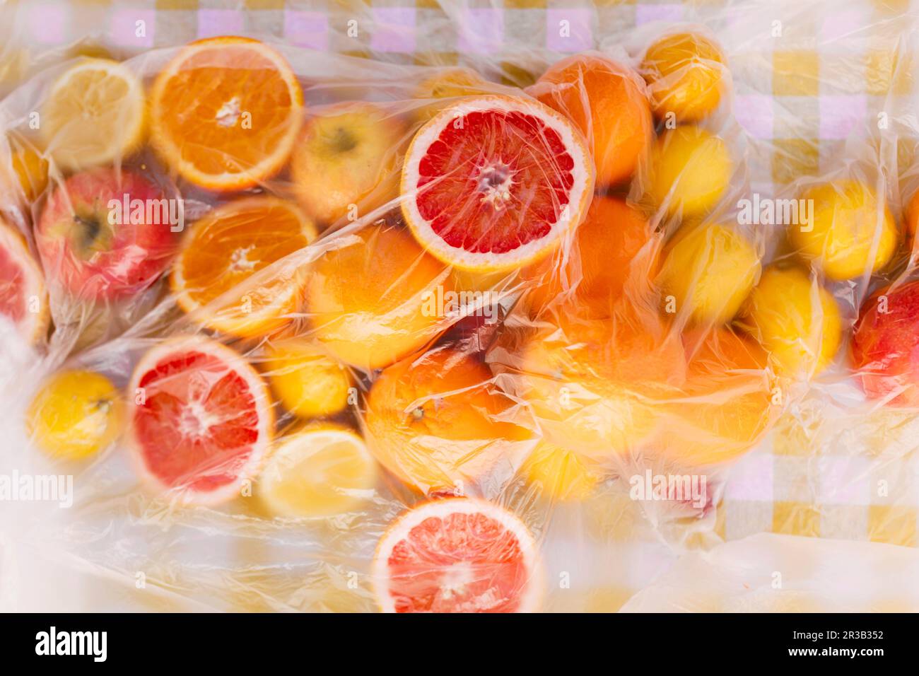 Frische Zitrusfrüchte auf dem Tisch, die mit Plastikfolie bedeckt sind Stockfoto