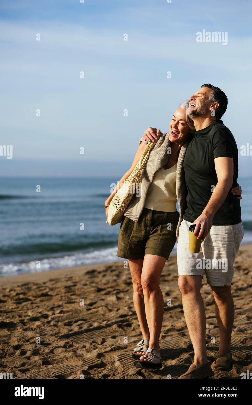 Sorgenfreies glückliches Paar, das am Strand spaziert Stockfoto