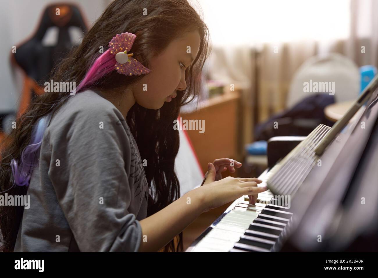 Ein Mädchen mit langen Haaren lernt Klavier zu spielen Stockfoto