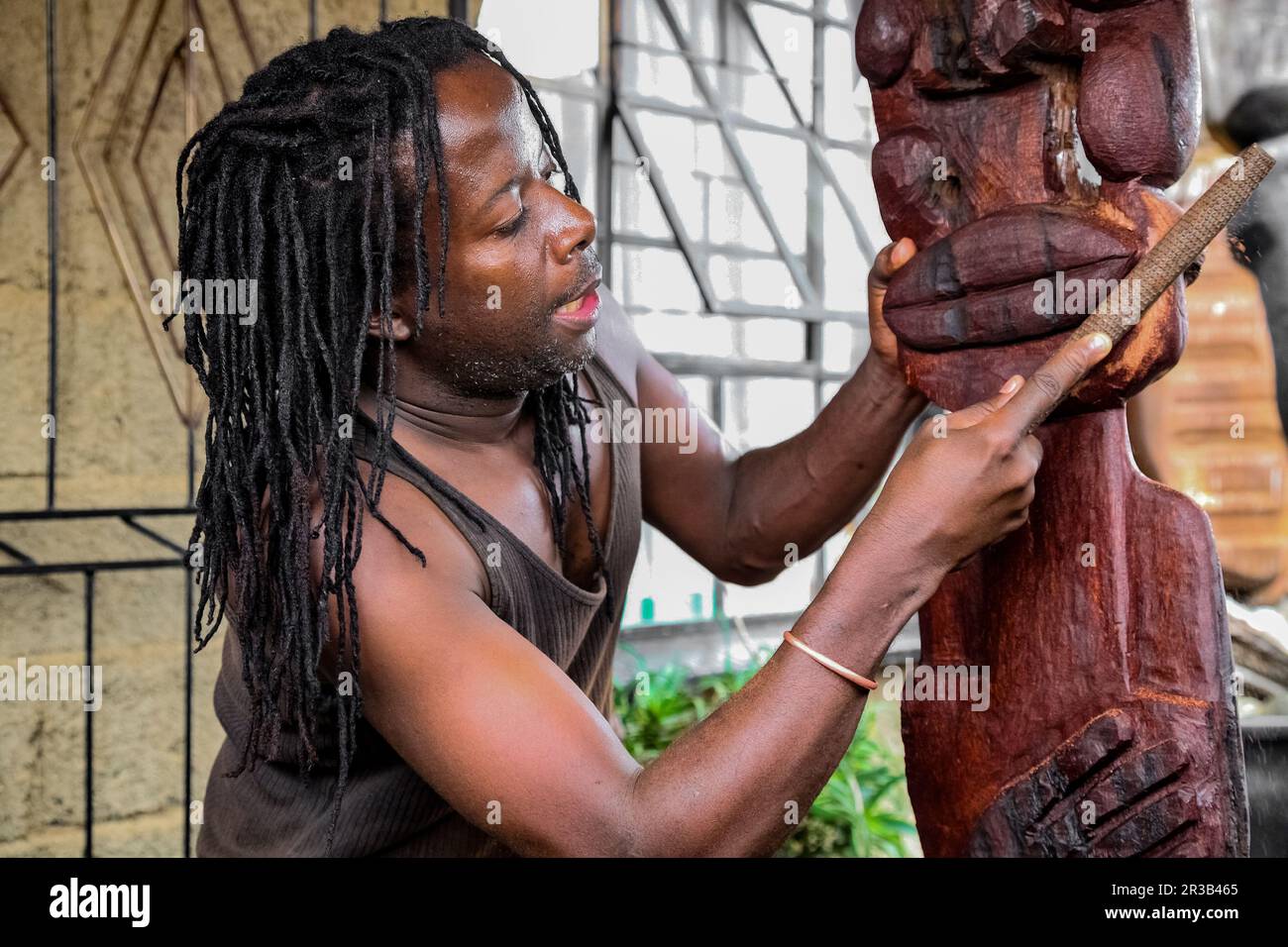 Afrikanischer Bildhauer, der eine traditionelle Statue aus Holz schnitzt Stockfoto