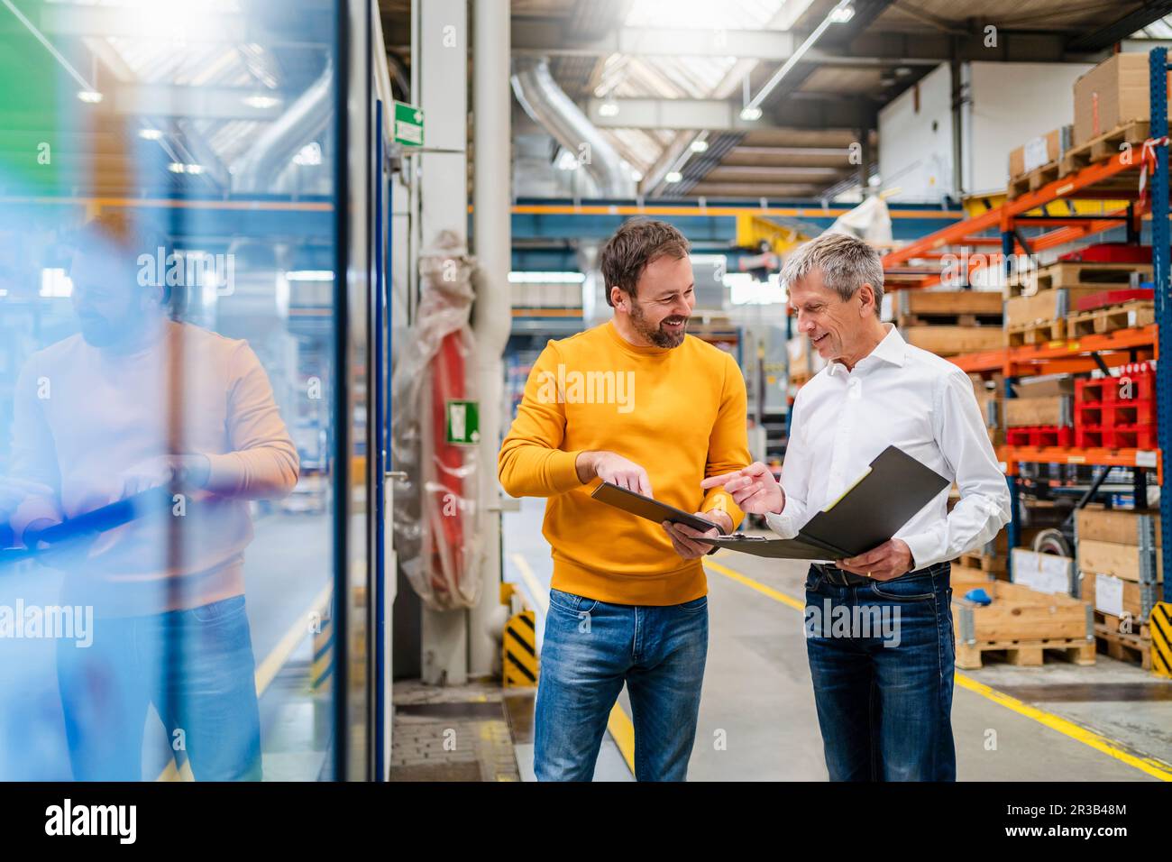 Lächelnde Geschäftskollegen planen in der Produktionshalle des Werks Stockfoto