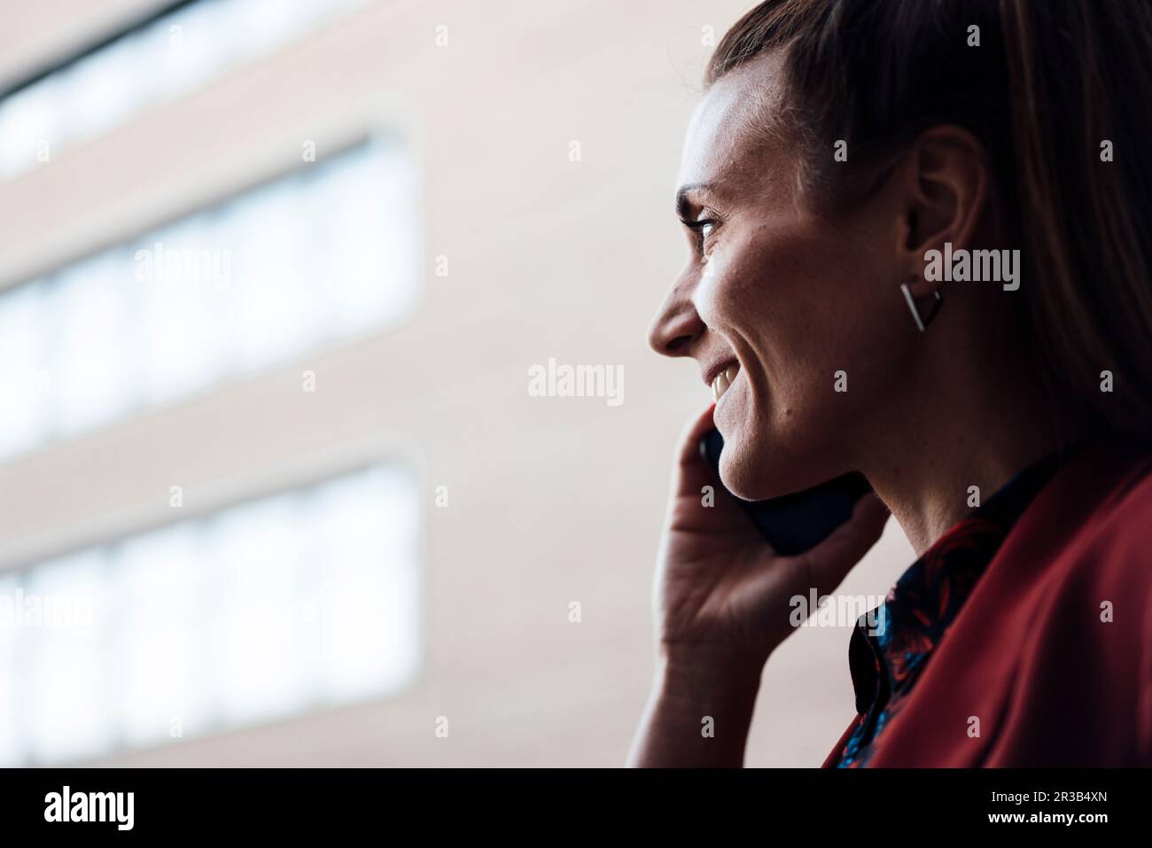 Lächelnde Geschäftsfrau, die über ein Mobiltelefon kommuniziert Stockfoto
