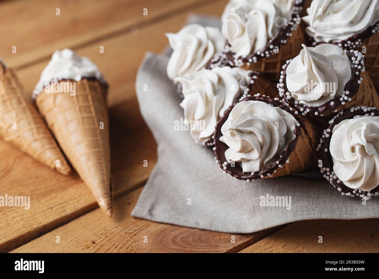 Viele Eiskegel auf einem Holztisch. Weicheis oder gefrorene Vanillesauce in Cones. Waffel-Marshma Stockfoto