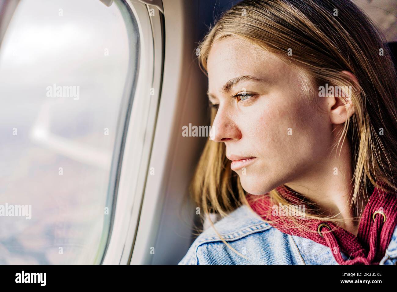 Junge Frau aus Flugzeugfenster Stockfoto
