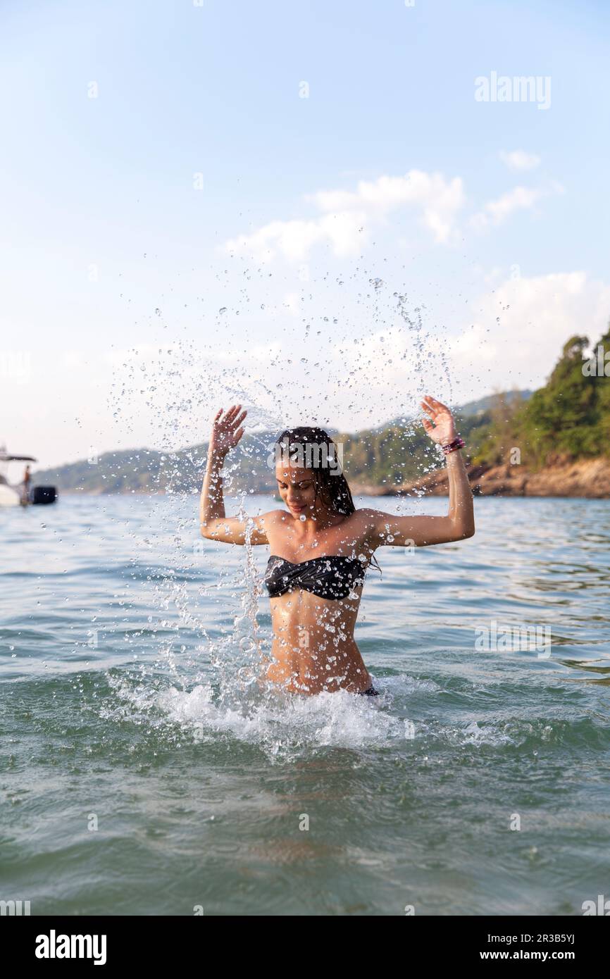 Eine Frau, die am Strand Wasser ins Meer spritzt Stockfoto