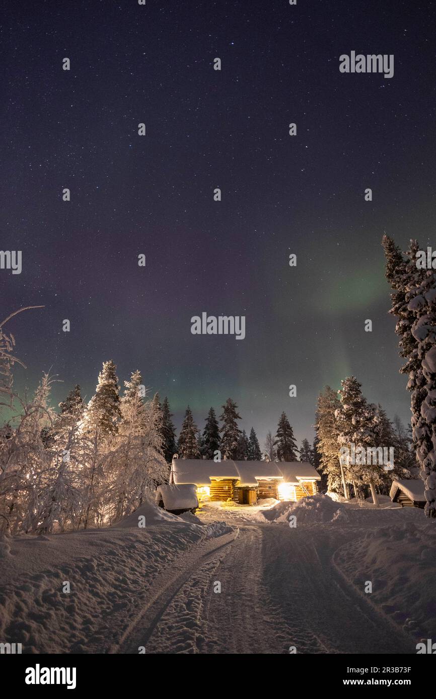 Reifenspuren auf der Schneestraße in Richtung des Nachthimmels der Aurora Borealis Stockfoto