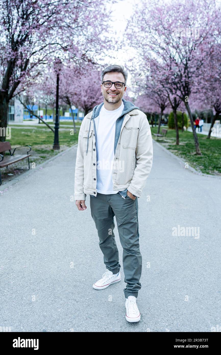 Lächelnder Mann mit Hand in der Tasche, der auf einem Fußweg im Park steht Stockfoto