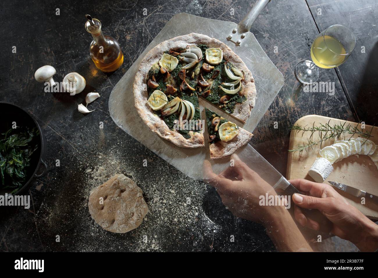 Dinkelmehlpizza mit Spinatpesto, Knoblauch, Zwiebeln, Pilzen, Rosmarin und Ziegenkäse Stockfoto