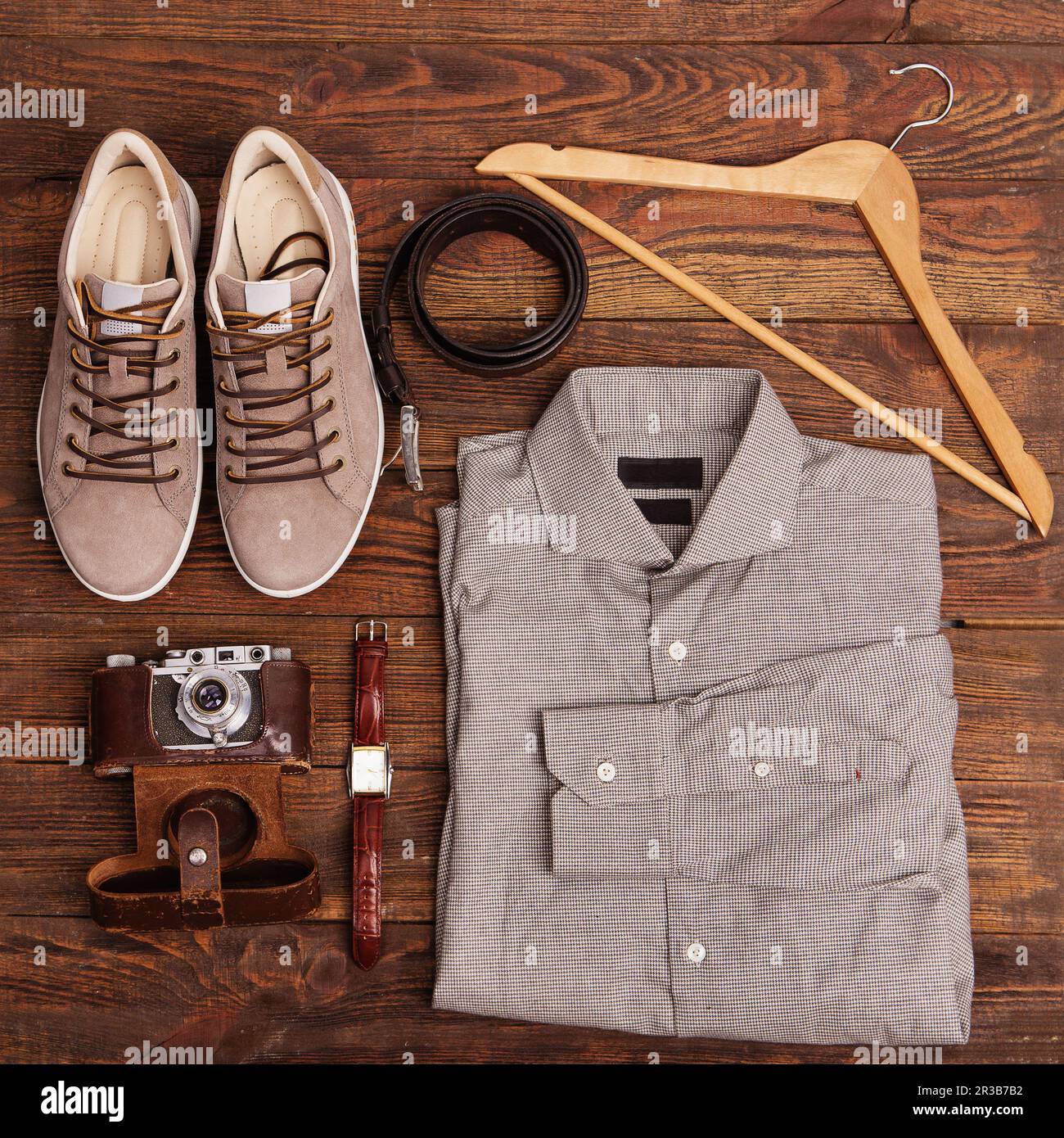 Flache Lagen moderner Herrenbekleidung auf braunem Holzhintergrund. Draufsicht auf Hipster-Kleidung und Acce Stockfoto