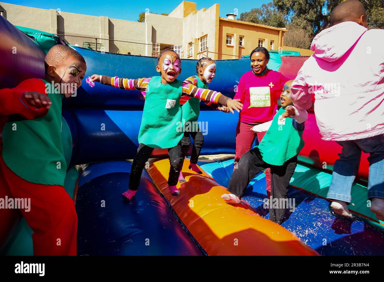 Junge afrikanische Vorschulkinder, die Spaß auf einem Springschloss auf dem Spielplatz haben Stockfoto
