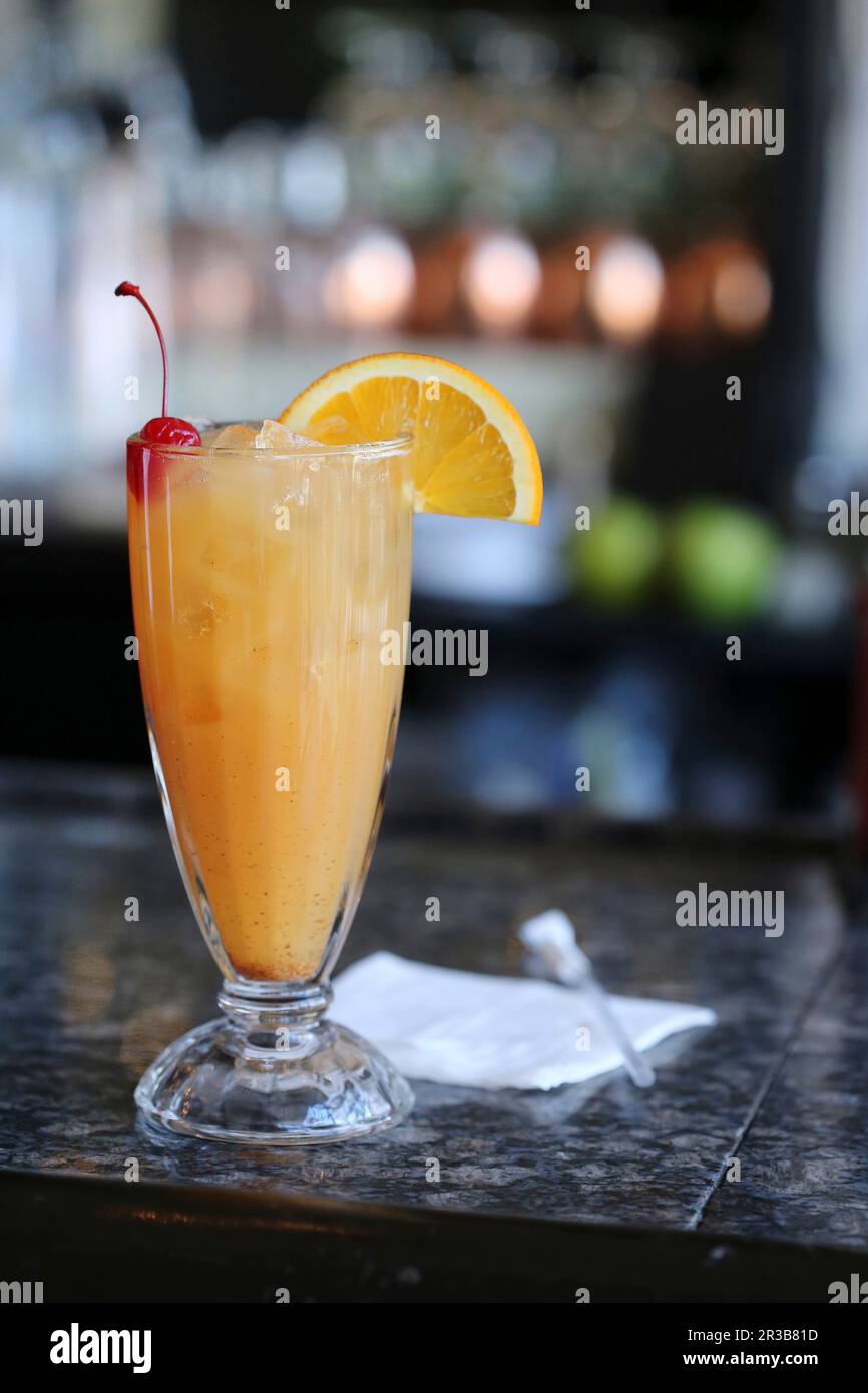 Rum-Punsch auf einer Bar mit einer Orangenscheibe und Marschino-Kirschgarnierung Stockfoto