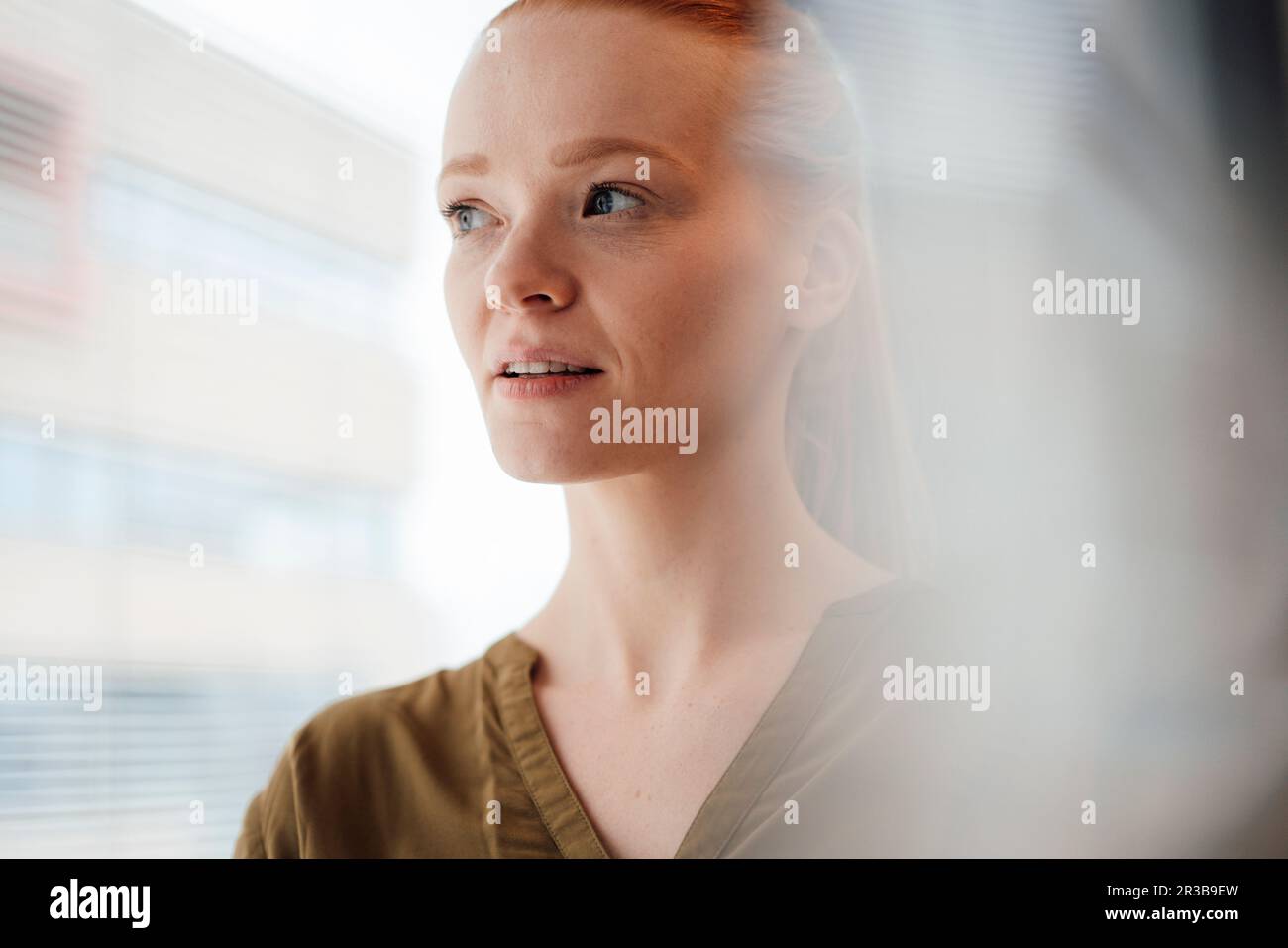 Junge Frau, die am Fenster denkt Stockfoto