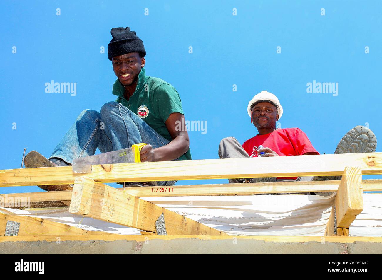 Verschiedene Mitglieder der Gemeinschaft bauen ein Billighaus in Soweto Stockfoto