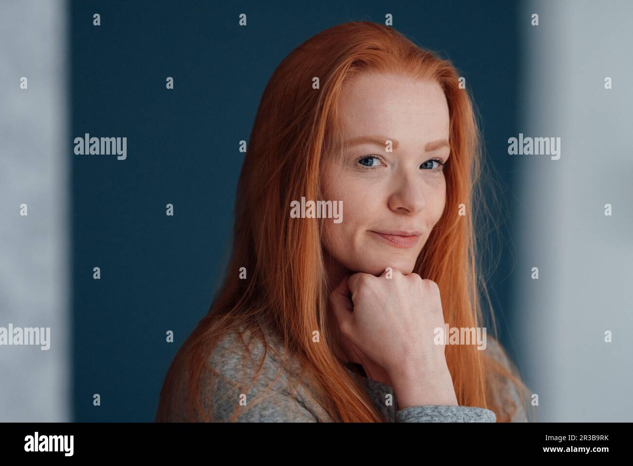 Rothaarige Frau mit Hand am Kinn Stockfoto