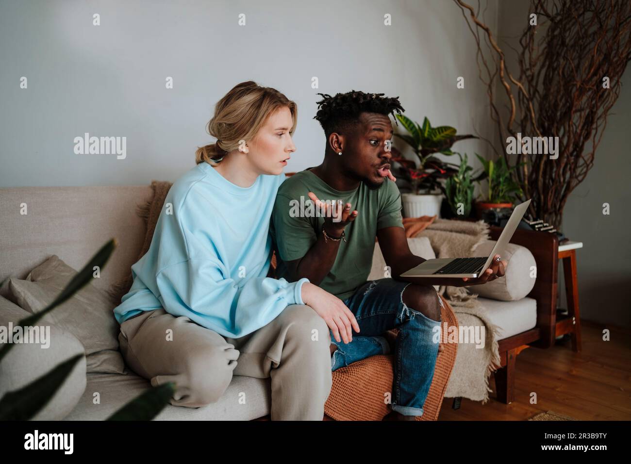 Mann und Frau, die Videoanrufe auf einem Laptop führen, sitzen zu Hause Stockfoto