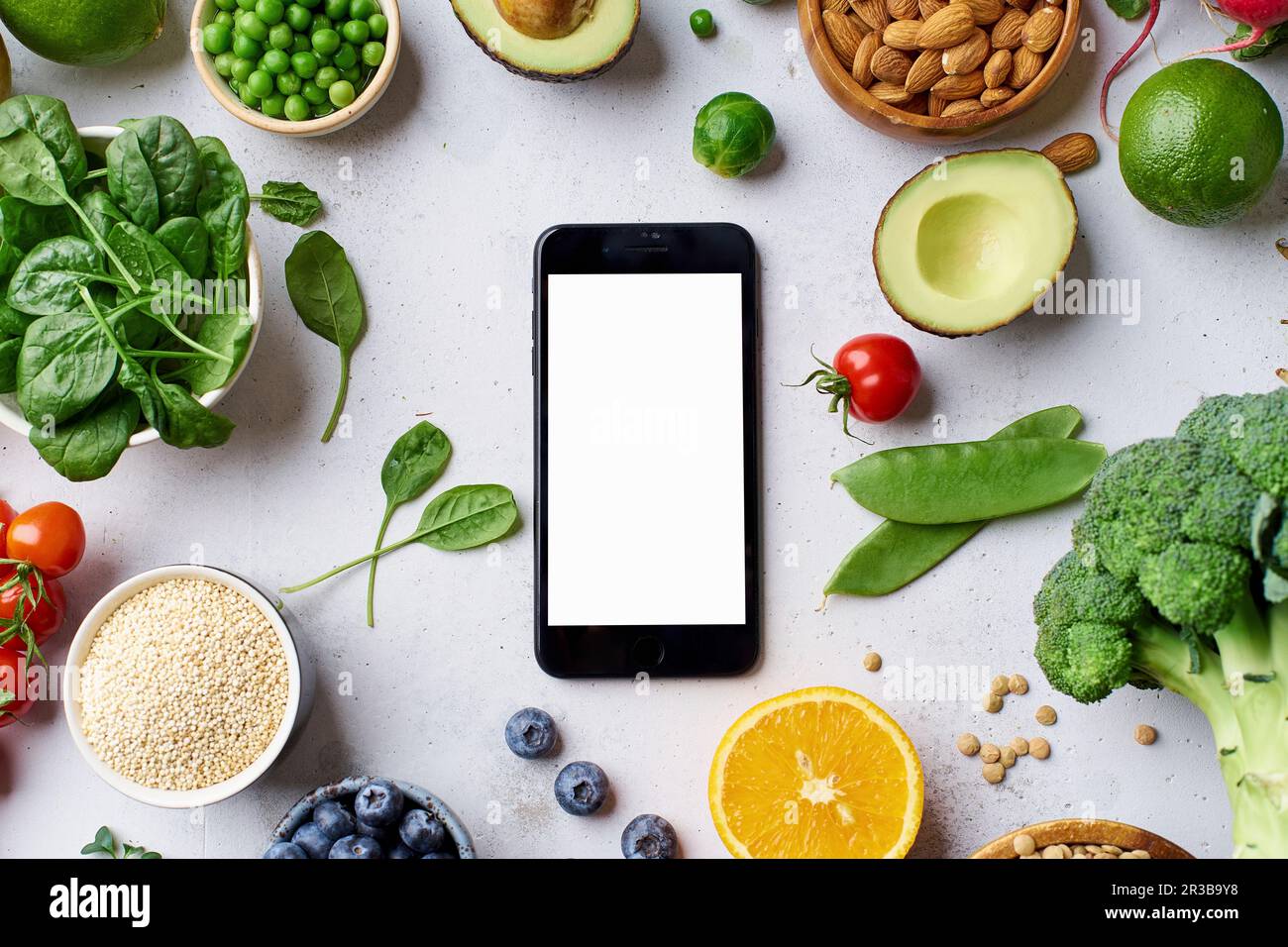 Gemüse, Obst, Linsen und Mandeln um ein Smartphone herum Stockfoto