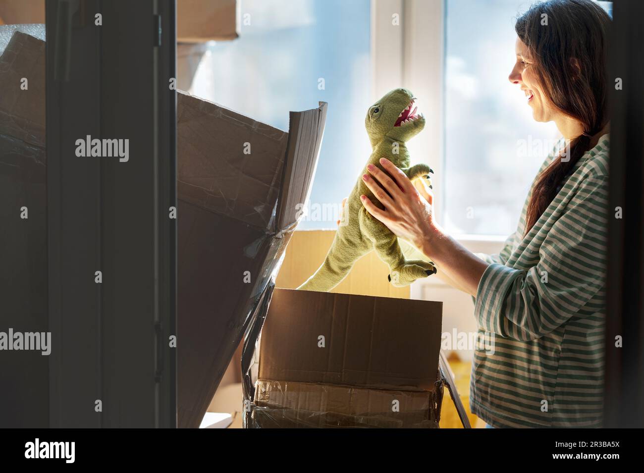 Lächelnde Frau, die Dinosaurierspielzeug in Kartons verpackt hat Stockfoto