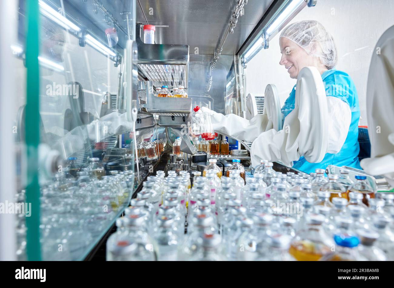 Wissenschaftler, der Chemikalienflaschen in mikrobiologischen Sicherheitsschränken hält Stockfoto