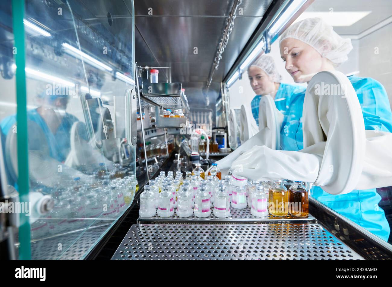 Wissenschaftler, die mit Chemikalienflaschen in mikrobiologischen Sicherheitsschränken arbeiten Stockfoto