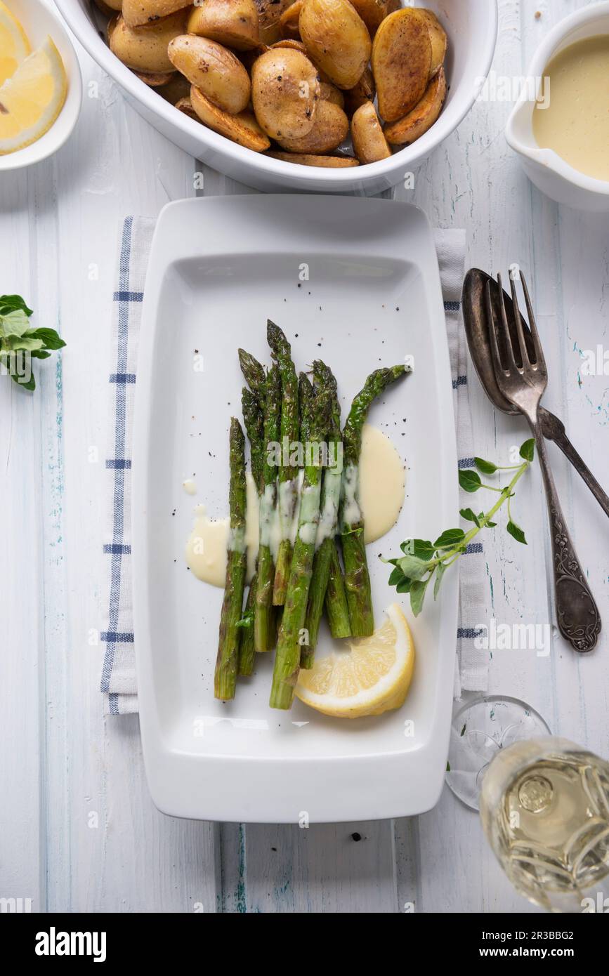 Gegrillter grüner Spargel mit veganer Sauce Hollandaise mit Mini-Bratkartoffeln Stockfoto