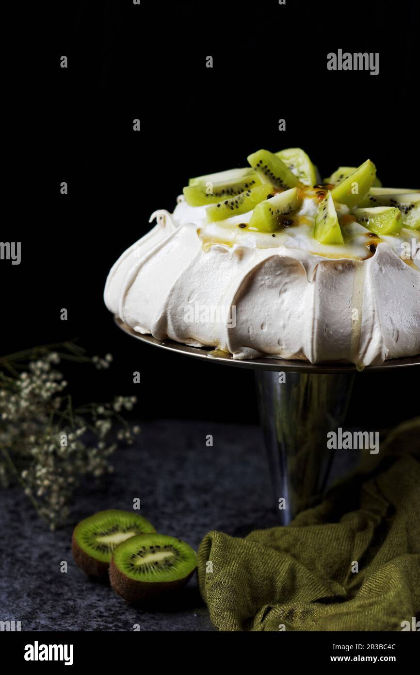 Pavlova mit Kokosnusscreme Kiwi und Passionsfruchtsauce Stockfoto