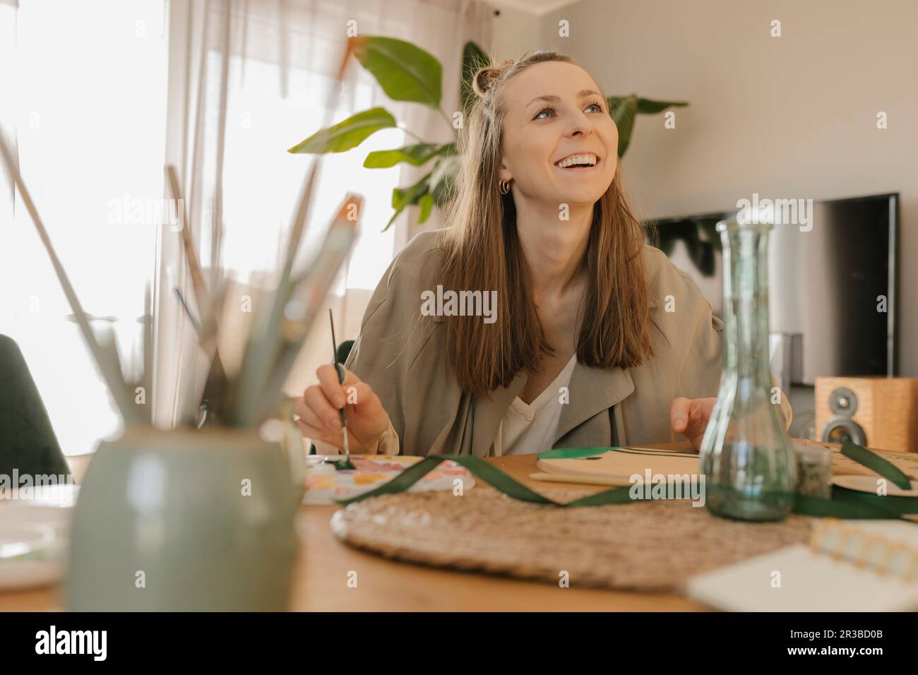 Glückliche junge Frau, die am Tisch malt Stockfoto