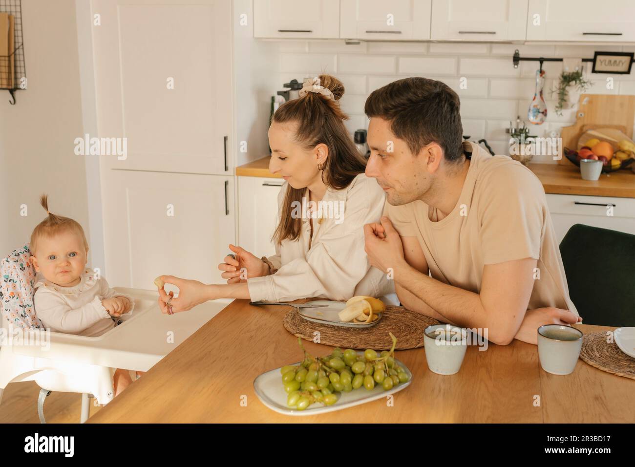 Vater und Mutter mit süßer Tochter, die zu Hause Obst isst Stockfoto
