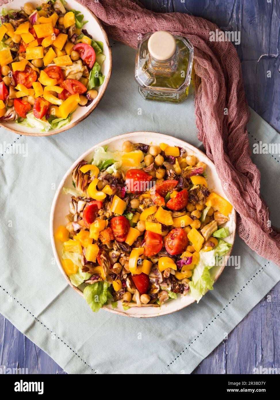 Schüssel mit heißem Salat auf Pflanzenbasis mit Kichererbsen, Paprika, Tomaten, roten Zichorien und Kurkuma Stockfoto