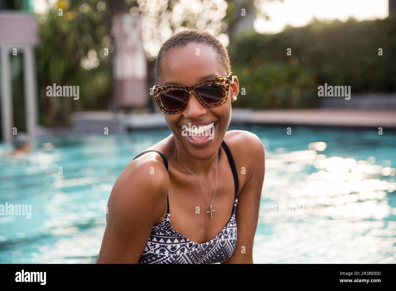Fröhliche Frau mit Sonnenbrille am Pool im Resort Stockfoto